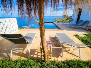 un par de sillas y una mesa junto a una piscina en Très belle villa avec piscine et vue incroyable sur mediterannée (DAR NAIM), en Tánger