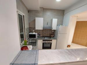 eine kleine Küche mit weißen Schränken und einem Kühlschrank in der Unterkunft حي الواحات in Tunis