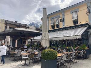 een patio met tafels en stoelen en een parasol bij Abeille de Chamonix in Chamonix-Mont-Blanc