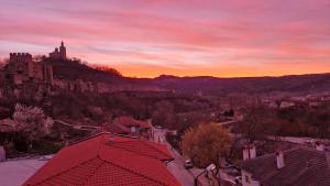 einen Sonnenuntergang über einer Stadt mit einem Schloss auf einem Hügel in der Unterkunft Къща за гости Великите in Weliko Tarnowo