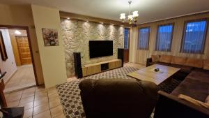 a living room with a couch and a television at Къща за гости Великите in Veliko Tŭrnovo