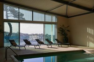 a room with chairs and a pool with a view at Fowey Hall - A Luxury Family Hotel in Fowey