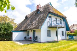 a thatched cottage with a patio and a balcony at Haus Hansi in Wieck
