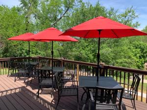 three tables and chairs with red umbrellas on a deck at Woodbridge Inn & Tavern in Jasper