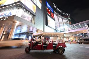 Une voiturette de golf rouge descend la nuit dans une rue de la ville. dans l'établissement Mövenpick Hotel Sukhumvit 15 Bangkok, à Bangkok