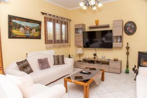 sala de estar con sofá blanco y TV de pantalla plana en Kapetanios Apartments, en Agios Stefanos