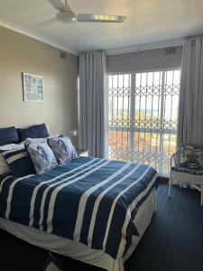 a bedroom with a bed and a large window at Dolphin View Self Catering in Scottburgh