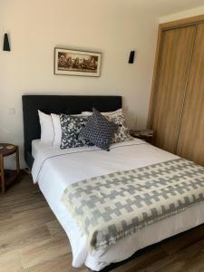 um quarto com uma grande cama branca com almofadas em A Beira Do Vale, Carvoeiro em Carvoeiro