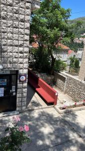 una panchina rossa seduta fuori da un edificio in pietra di HI Hostel Dubrovnik a Dubrovnik