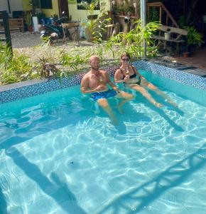 a man and a woman sitting in a swimming pool at Babu Backpackers inn in Moalboal
