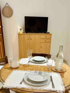 a table with plates and wine glasses and a tv at la Maison Jaune in Cagnes-sur-Mer