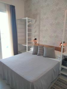 una camera con un letto bianco e un muro di Albergo Aquila a Rimini