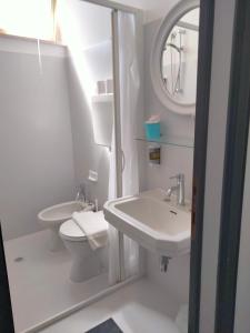 W łazience znajduje się umywalka, toaleta i lustro. w obiekcie Albergo Aquila w Rimini