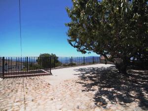 a tree and a fence with the ocean in the background at Belvilla by OYO Casa Almendro in La Joya