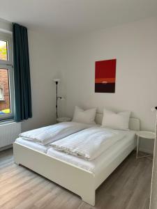 Cama blanca en habitación con ventana en Hotel DH -Deutsches Haus- en Emden