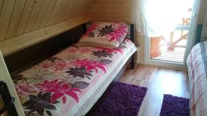 a small bed in a wooden room with purple rugs at Ośrodek Admirał Wicie in Wicie
