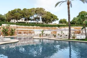 - une piscine dans un complexe avec des chaises et des palmiers dans l'établissement AluaSoul Mallorca Resort - Adults only, à Cala d´Or