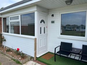 a screened in porch on a house with two chairs at 141 -Two bed Chalet on Sunbeach Holiday Park - Sleeps 6, pet friendly, FREE pool and entertainment passes included - plus WiFi with bedding and towels included - only 300m from the beach! in Scratby