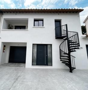 uma casa branca com escadas pretas e uma garagem em LA MAISON DE MARIE A 8 mn des plages em Perpignan