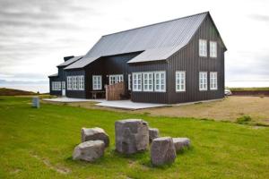 una gran casa negra con rocas en un campo en Day Dream Hellnar en Snæfellsbær