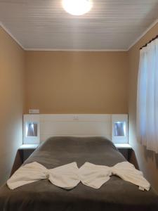 a bedroom with a bed with two white sheets at Pousada Château dos Fontes in Campos do Jordão