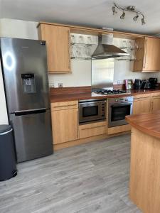 a kitchen with a stainless steel refrigerator and wooden cabinets at 2 bed city centre executive apartment in Aberdeen