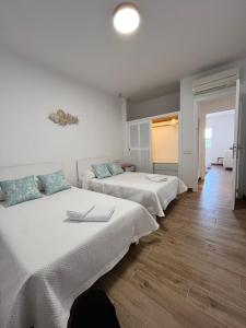 two beds in a room with white walls and wooden floors at Apartamento en Costamar I, 2ª Planta, 23 in Es Pujols
