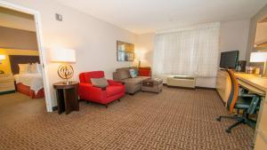 um quarto de hotel com uma cama e uma cadeira vermelha em TownePlace Suites by Marriott Scranton Wilkes-Barre em Moosic