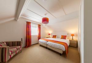 een slaapkamer met een bed en een bank bij Hotel-Restaurant de Boer'nkinkel in Hoenderloo