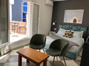 a bedroom with a bed and two chairs and a table at riad casa bahia asilah in Asilah