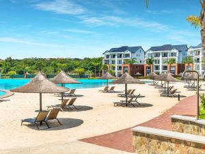 a beach with chairs and umbrellas and a pool at 5 The Blyde Crystal Clear 2 Bedroom Apartment in Pretoria