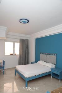 1 dormitorio con cama y pared azul en NARCISSE RESIDENCE, en Hammam Sousse