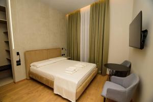 a bedroom with a bed and a chair and a television at Hotel Zeneli Vlore in Vlorë