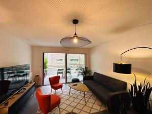 ein Wohnzimmer mit einem Sofa, einem Tisch und Stühlen in der Unterkunft L’Hermine, parking & terrasse in Concarneau