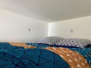 uma cama com um edredão e almofadas azuis e brancas em L’Hortense em Oloron-Sainte-Marie