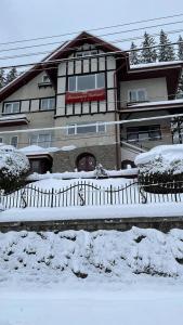 a building with snow on the ground in front of it at Pensiunea Vila Gabriel in Sinaia