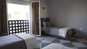 a bedroom with two beds and a sliding glass door at riad casa bahia asilah in Asilah