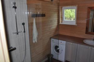 a bathroom with a shower and a washing machine at Muratsi Holiday Cottages in Kuressaare