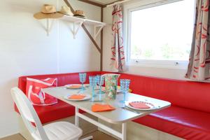 een eetkamer met een witte tafel en een rode bank bij Le Clos Tranquille in Saint-Cast-le-Guildo