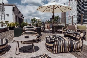 un patio con sillas, una mesa y una sombrilla en Gekko House Frankfurt, a Tribute Portfolio Hotel en Frankfurt