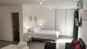 a white bedroom with a bed and a couch at Sttanze Giardino in Posadas