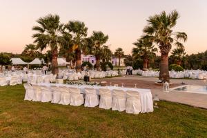 a row of tables with white chairs and palm trees at Crown Royal Luxury Villa Estates in Rhodes Town +36 photos
