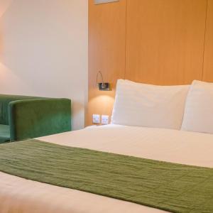 a bedroom with a bed and a green chair at Station House Hotel Letterkenny in Letterkenny