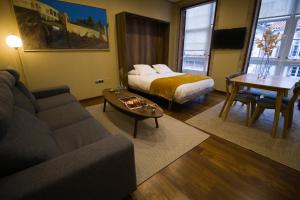 a living room with a bed and a couch and a table at Apartamentos Turísticos Pacios in Santiago de Compostela