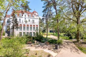 una vista esterna di una grande casa bianca con alberi di Pineblue Villas a Heringsdorf
