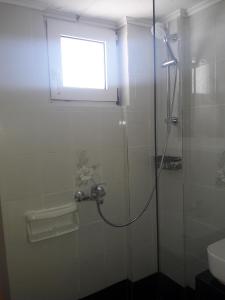 a bathroom with a shower with a window and a sink at Ambrosia studios in Makry Gialos