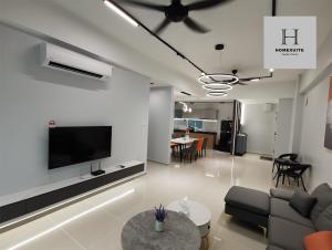 a living room with a couch and a tv on a wall at Homexuite Vacation @ Sri Indah in Sandakan