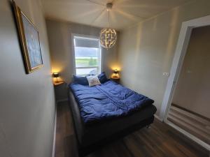 a bedroom with a bed with a blue comforter and a window at Ásgarður in Hrísey