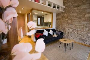 a living room with a black couch and a stone wall at Apartamentos Turísticos Pacios in Santiago de Compostela