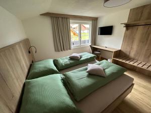 een slaapkamer met 2 groene bedden en een bureau bij Appartement Ski-Willy in Ramsau am Dachstein